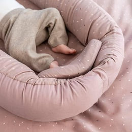 Cozy Nest baby nest in sand color with soft padding, providing comfort for a newborn's play and sleep.