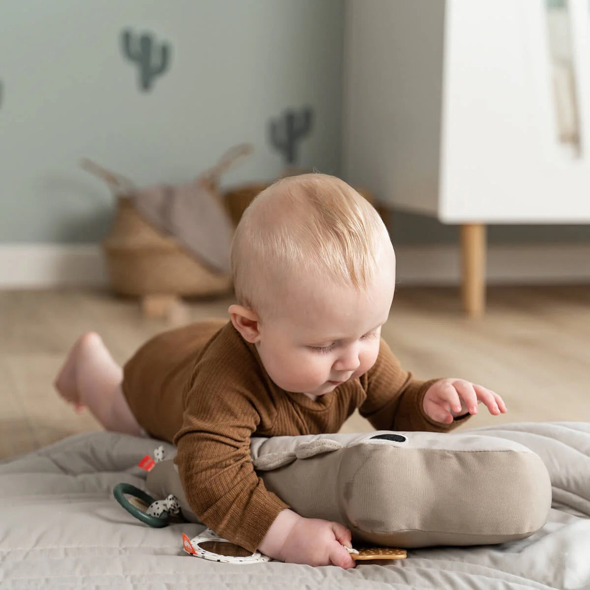 Baby enjoying tummy time on Croco activity toy in sand color, encouraging sensory play and neck strength.