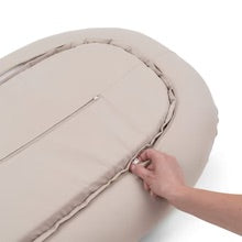 Hand adjusting the zipper on the Cozy Nest - Sand by Done By Deer, a luxurious baby nest for comfort and safety.